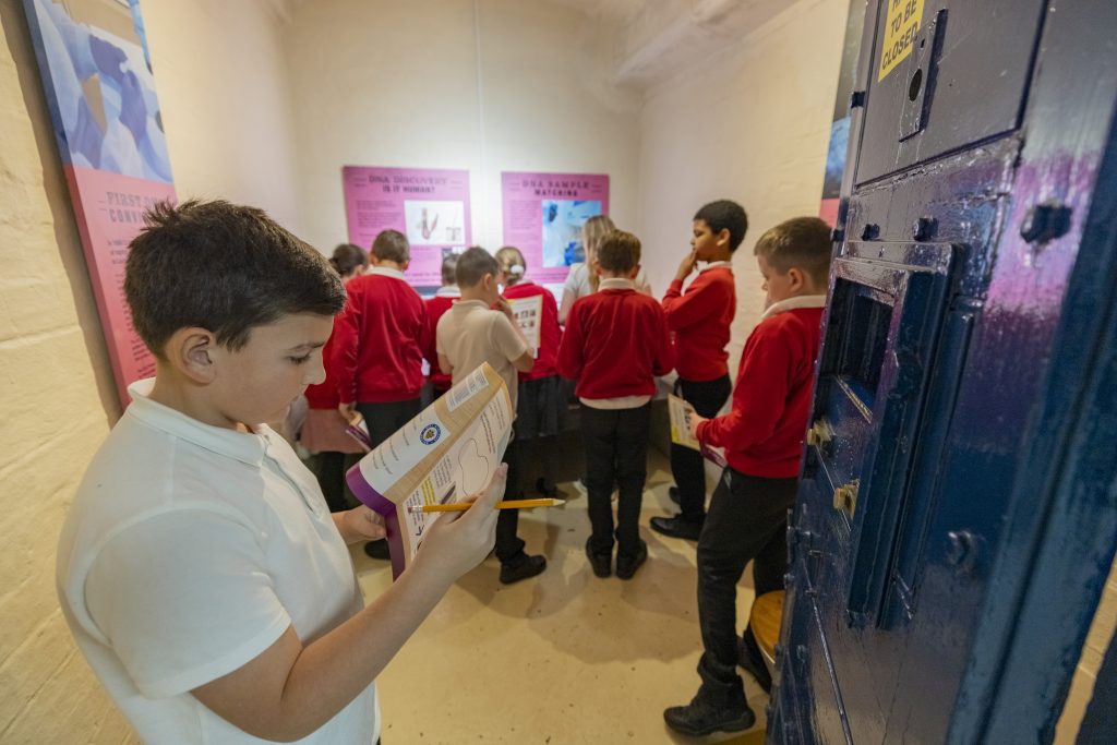 a group of school children in the forensics display room, working on their forensics trail